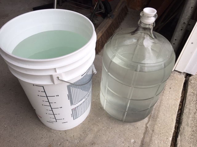 Plastic bucket and glass carboy full of water