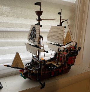A Lego pirate ship with two masts. The main sail on the front mast has a skull and crossbones. At the helm is a Waldorf minifigure