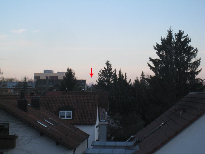 View of a mountain peaking between houses and trees