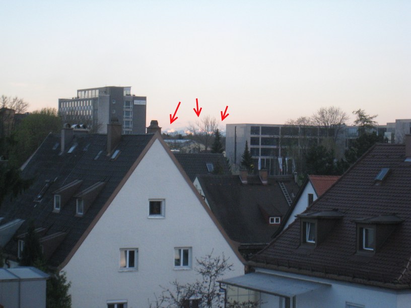 View of a few mountains peaking between buildings