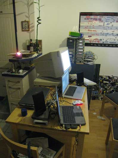 Dining table with two laptops and one desktop on it and two AlphaServers behind it