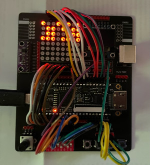 HackerBox 0088 - FPGA lab - a circuit board with an 8x8 LED matrix, a small screen, an FPGA module, dip switch, buttons, potentiometer, jumper cables connecting things